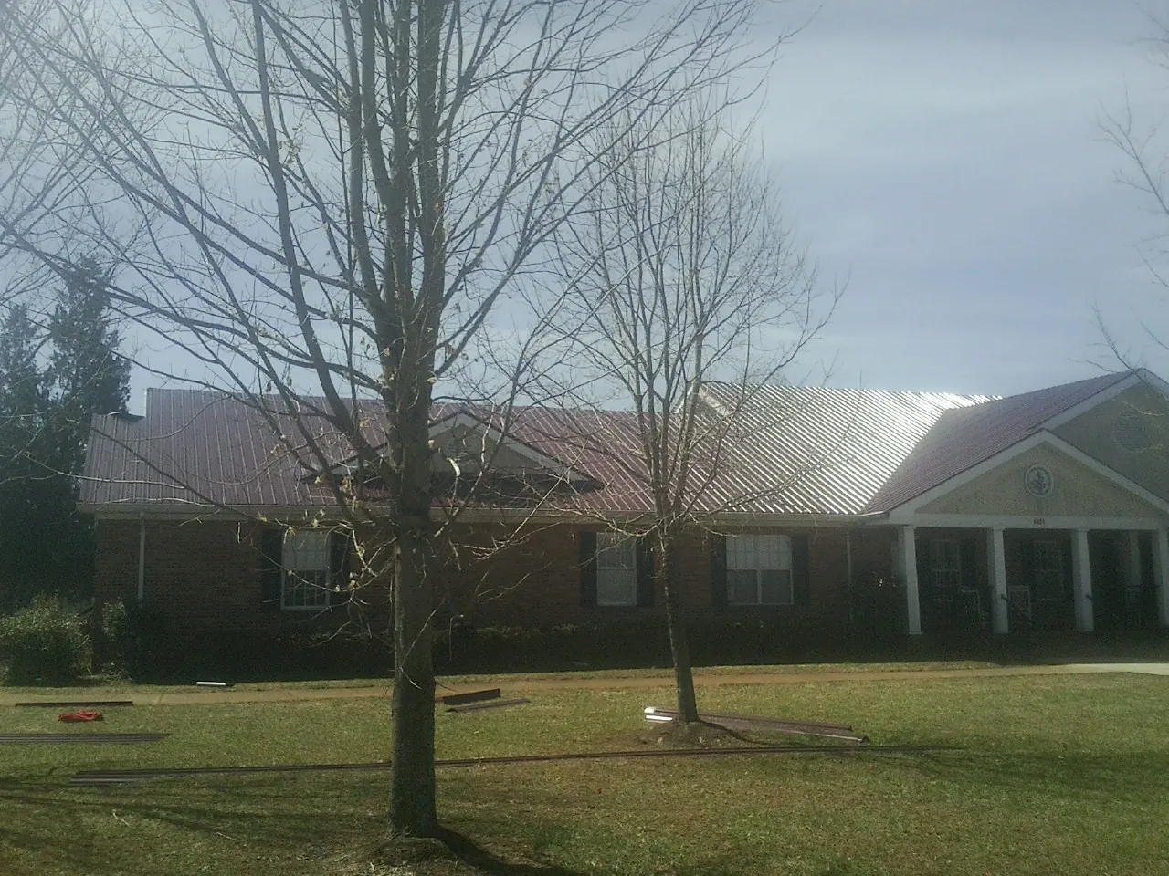 Red metal roof on a brick building seen from the front lawn in Grovetown