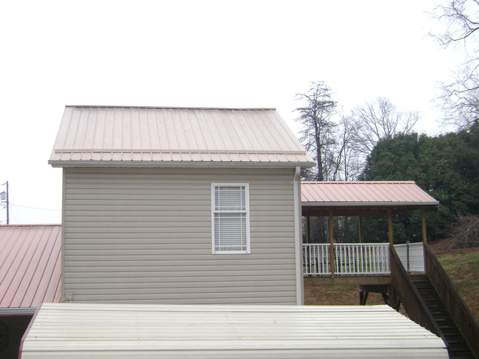 Tan metal roofs on a two story addition and attached porch, from a Roof Replacement job in Grovetown
